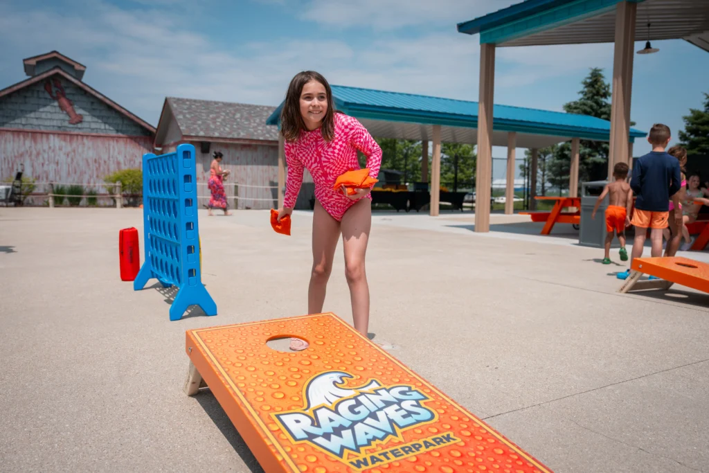 Girl playing cornhole at Raging Waves